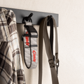 Grey football dog collar hanging on a wall hook with a shirt and leash