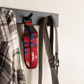 Red and blue football dog collar hanging on a wall hook with a shirt and leash