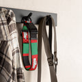 Black, red & green football dog collar hanging on a wall hook with a shirt and leash