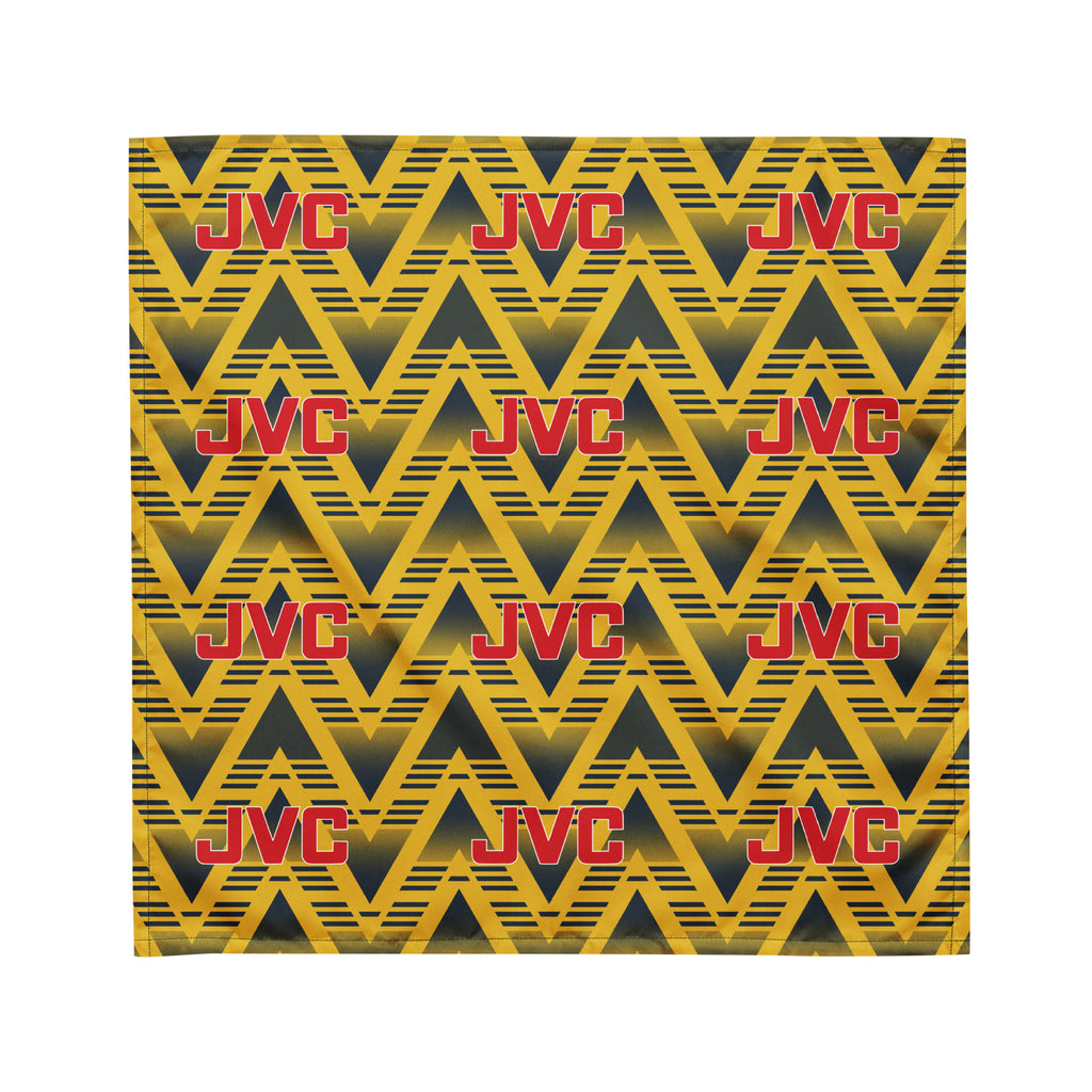 A square fabric or paper product featuring a repeating geometric pattern of yellow and black zigzags with red JVC logos across the surface, shown against a plain white background.