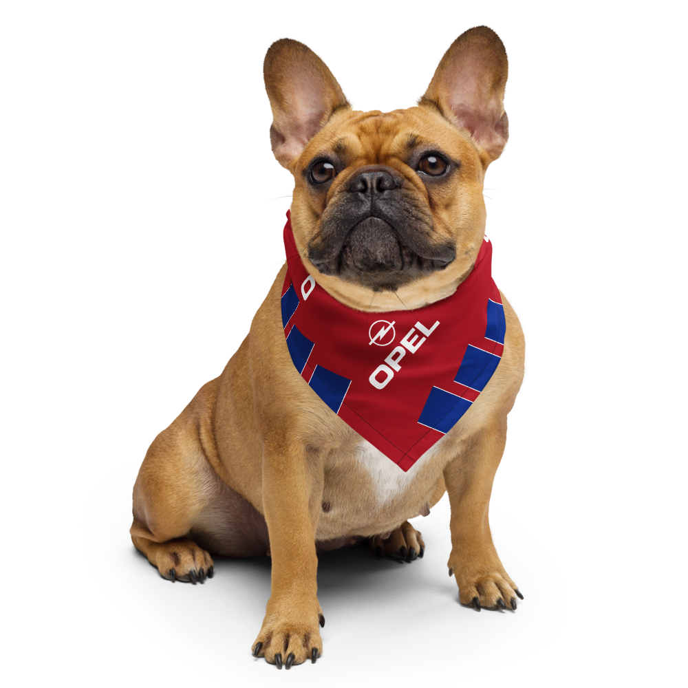 A fawn French Bulldog wearing a red and blue bandana with the white Opel logo, photographed against a seamless white background.