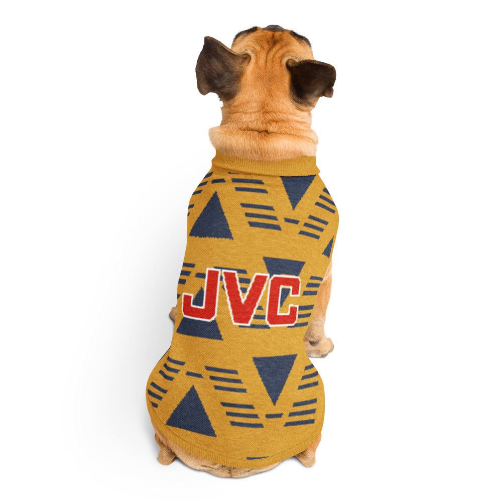 A small tan dog viewed from behind wearing a yellow knit pet sweater with a navy geometric pattern and a red 'JVC' logo on the back, photographed on a clean white background.