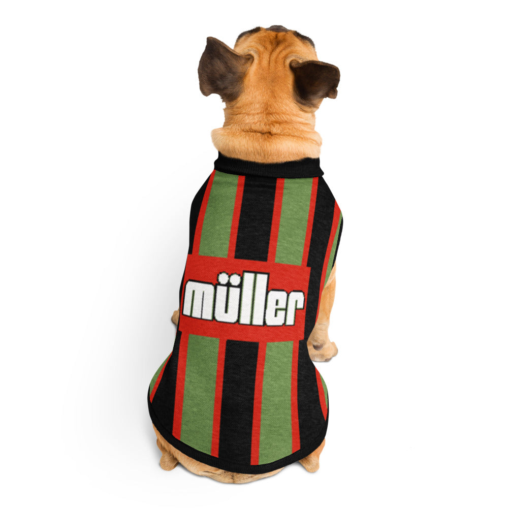 A small tan dog viewed from behind wearing a striped pet shirt with green, black, and red vertical stripes and a red center panel with the word 'müller' in white.