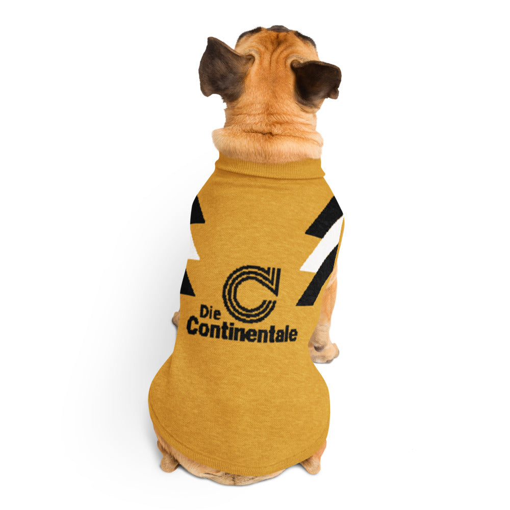 A small tan dog viewed from behind wearing a mustard yellow pet shirt with black and white graphic stripes and a black 'Die Continental' logo on the back, against a plain white background.