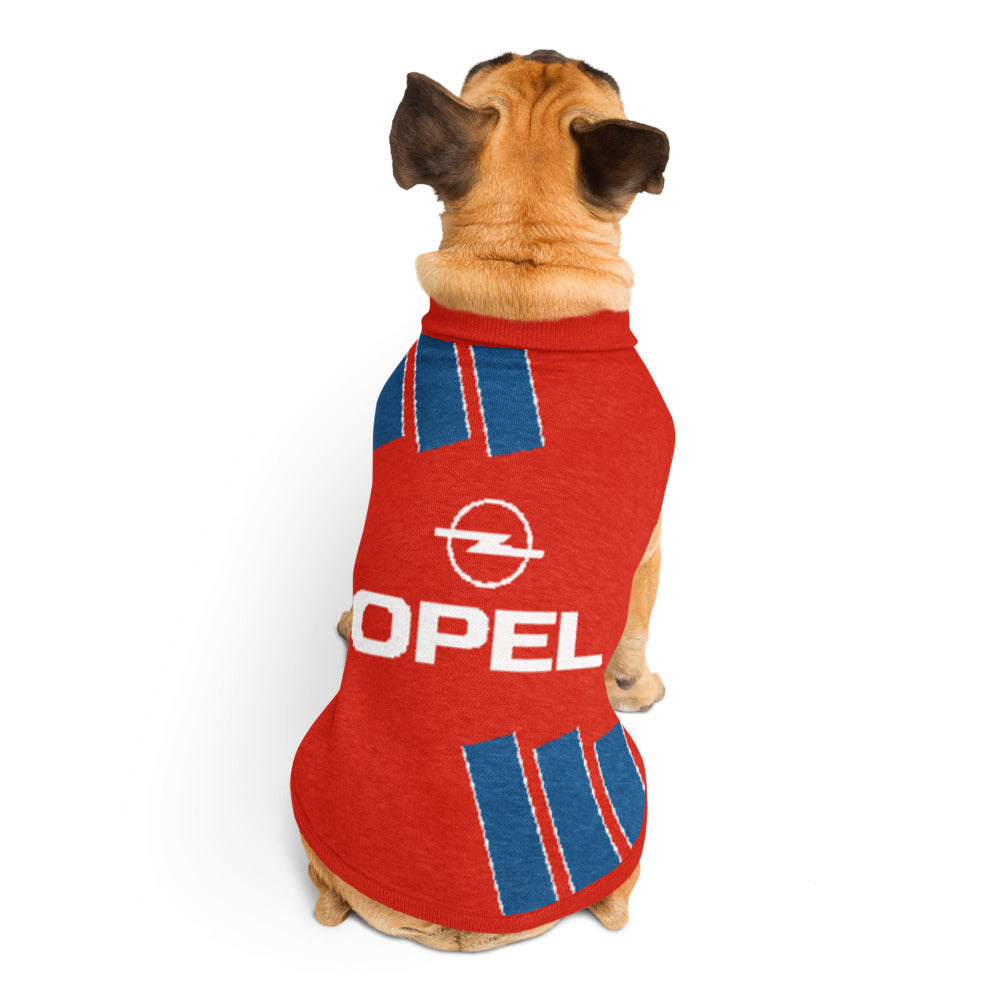 A small tan dog viewed from behind wearing a red pet shirt with blue stripes and a white Opel logo, photographed on a clean white background.