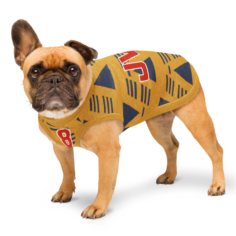 A fawn French bulldog wearing a mustard yellow knit dog sweater with navy blue geometric patterns and red lettering, standing against a white background.