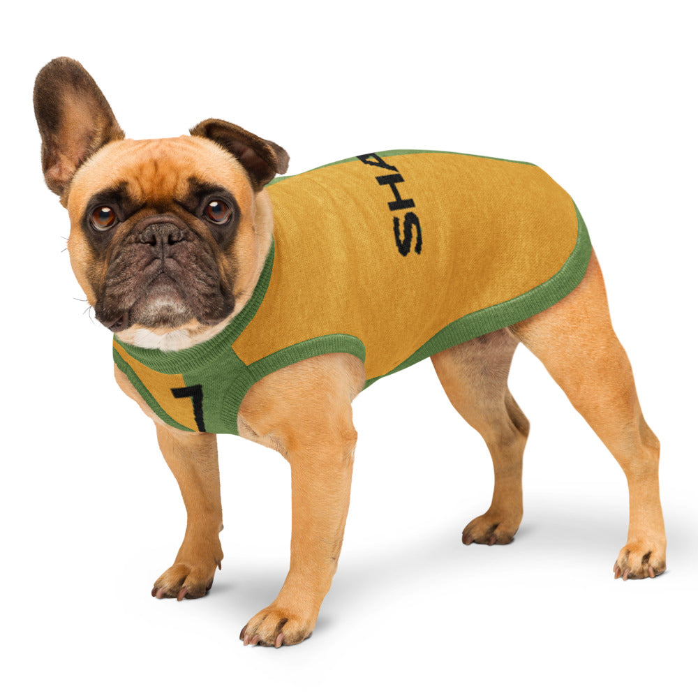 A fawn French Bulldog wearing a mustard yellow and green dog sports jersey with black lettering, standing against a white studio background.