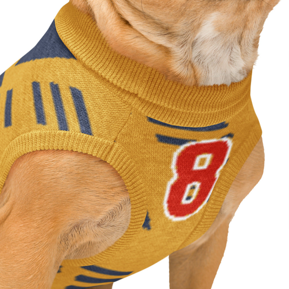 A close-up of a dog wearing a mustard yellow knit sweater with navy blue stripes and a red number 8 on the side, set against a plain white background.