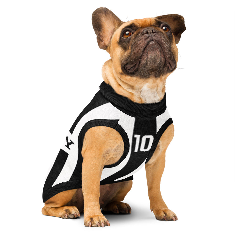 A fawn French bulldog wearing a black and white soccer jersey-style dog sweater with the number 10, photographed against a clean white background.